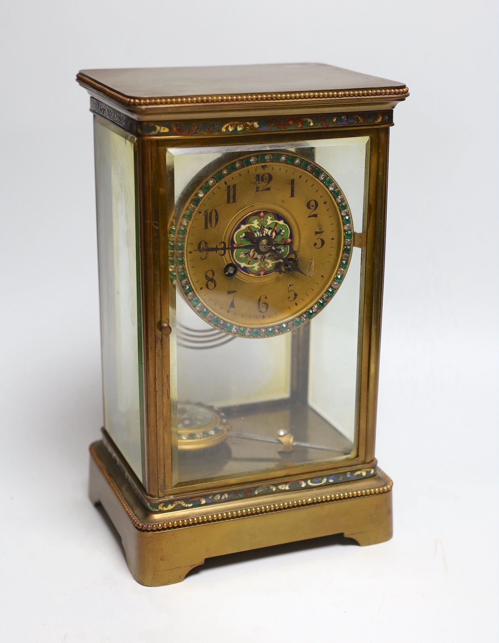 An early 20th century four glass brass and champleve enamel clock, with decorative enamelled and paste dial and pendulum, 7cms wide, 28cms high